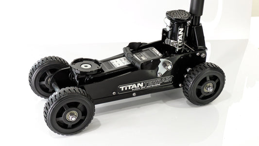 A black rugged floor jack with a hydraulic pump and four large wheels, designed for off-road conditions.